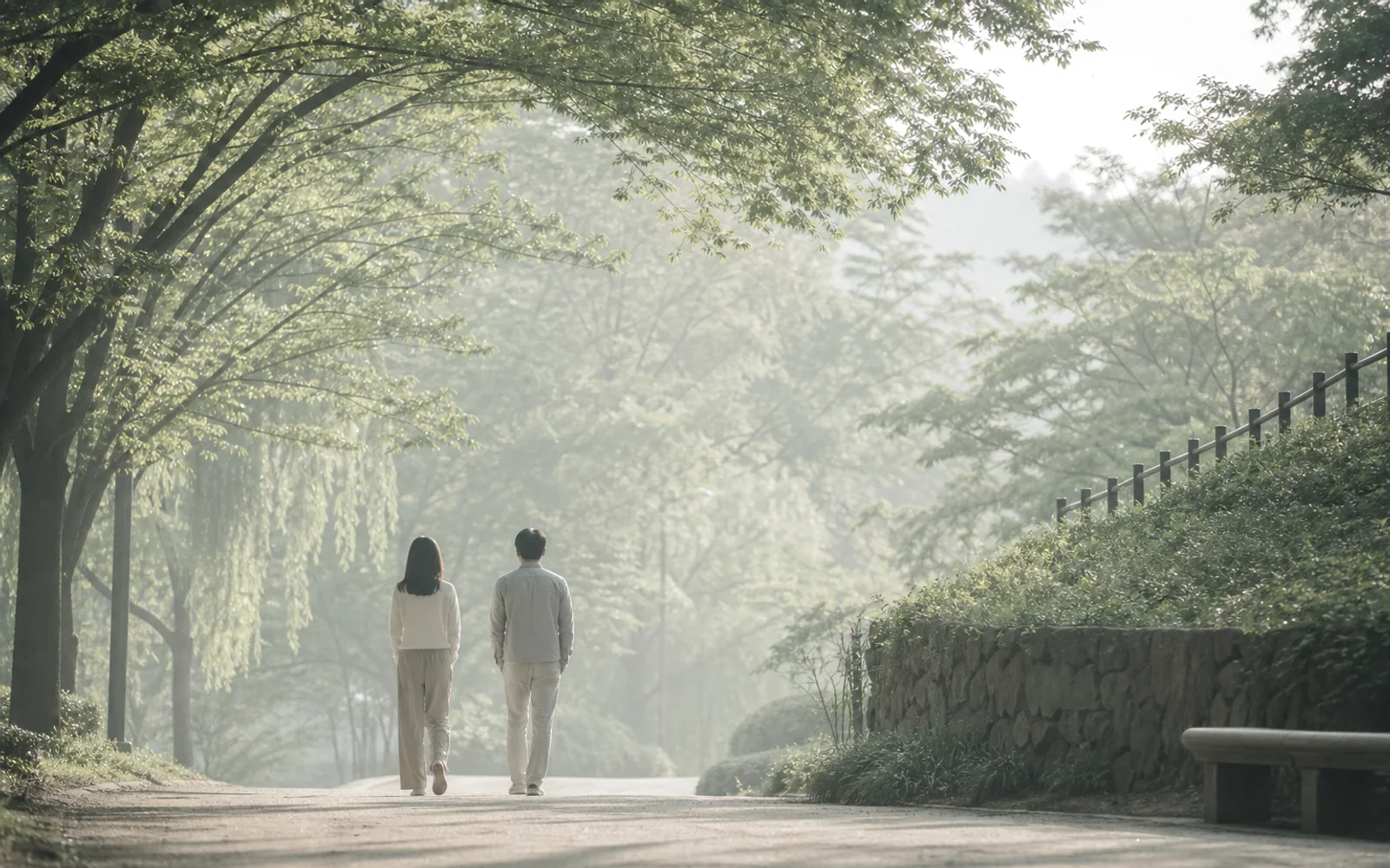 나무 아래를 천천히 걷는 두 사람
